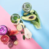 bottiglie di vetro con bevande naturali su una parete colorata min